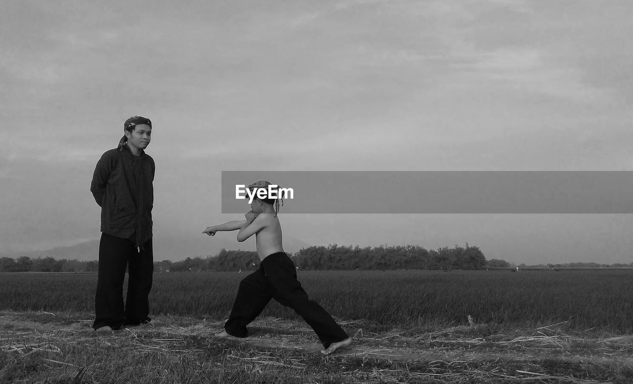 Man looking at son practicing martial arts on field