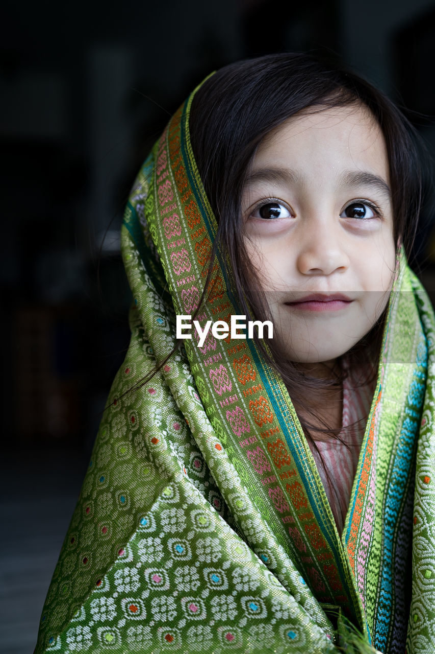 Portrait of cute asian toddler, kid, girl wearing traditional songket shawl.