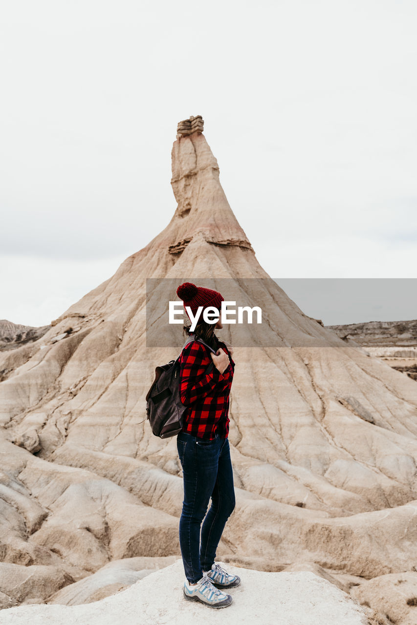 Spain, navarre, female tourist standing in front of sandstone rock formation in bardenas reales