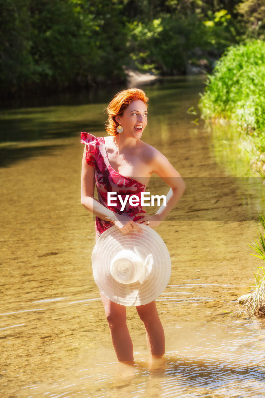 Smiling woman looking away while standing in water