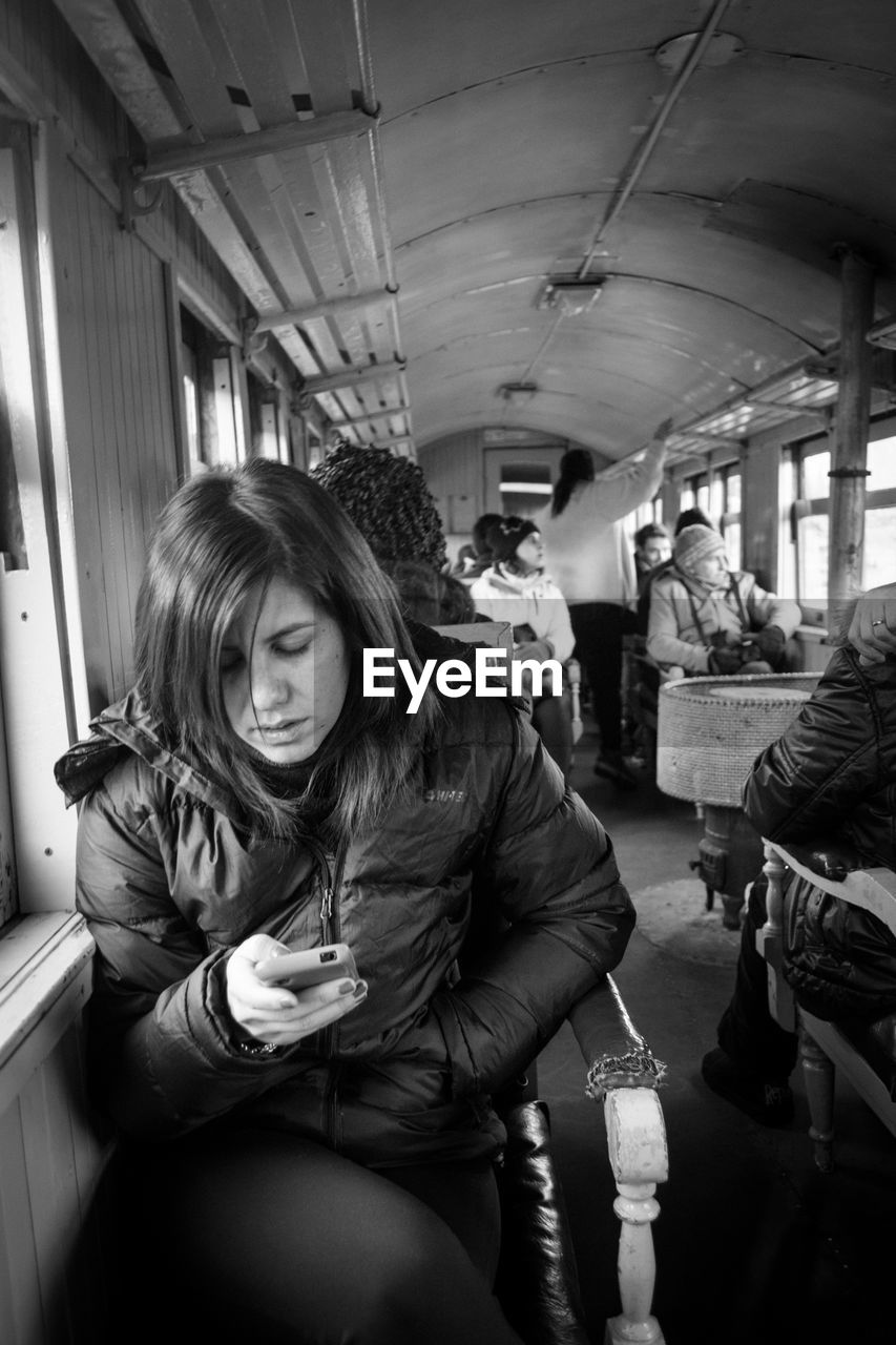 Woman using mobile phone while sitting in train