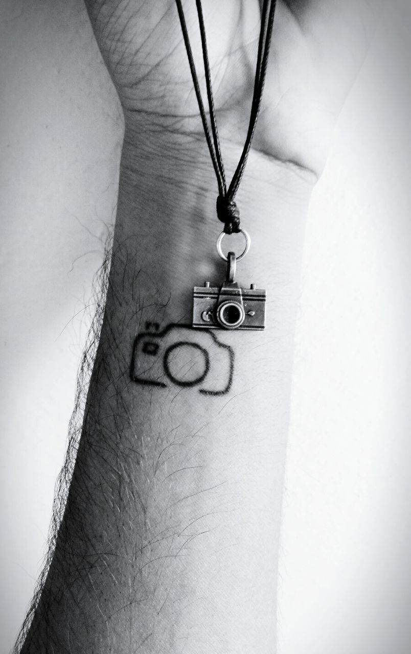 Close-up of tattooed hand with camera necklace