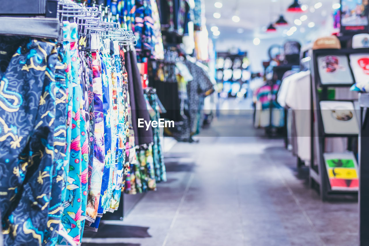 retail, store, shopping, multi colored, hanging, clothing, consumerism, clothing store, focus on foreground, fashion, variation, market, business, city, abundance, in a row, indoors, large group of objects, no people, business finance and industry
