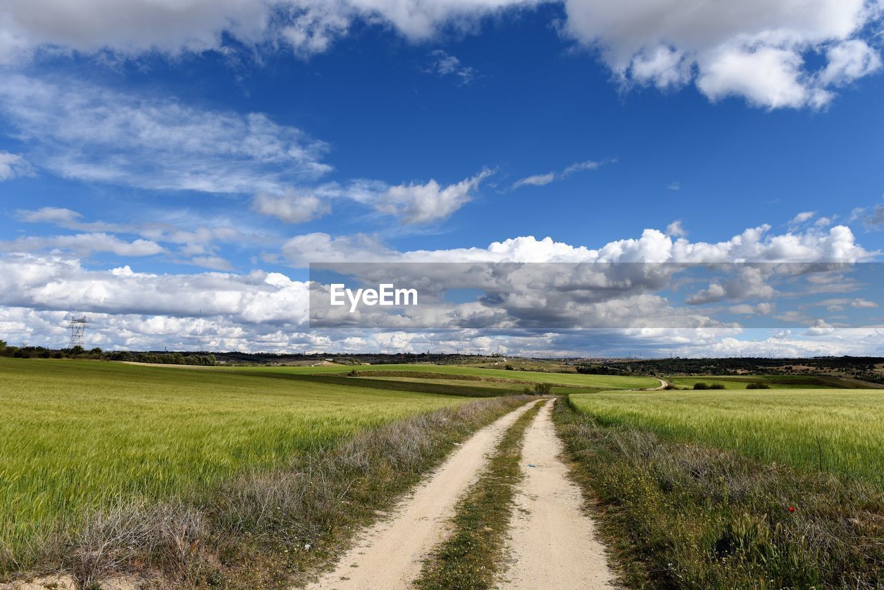 Road amidst field against sky