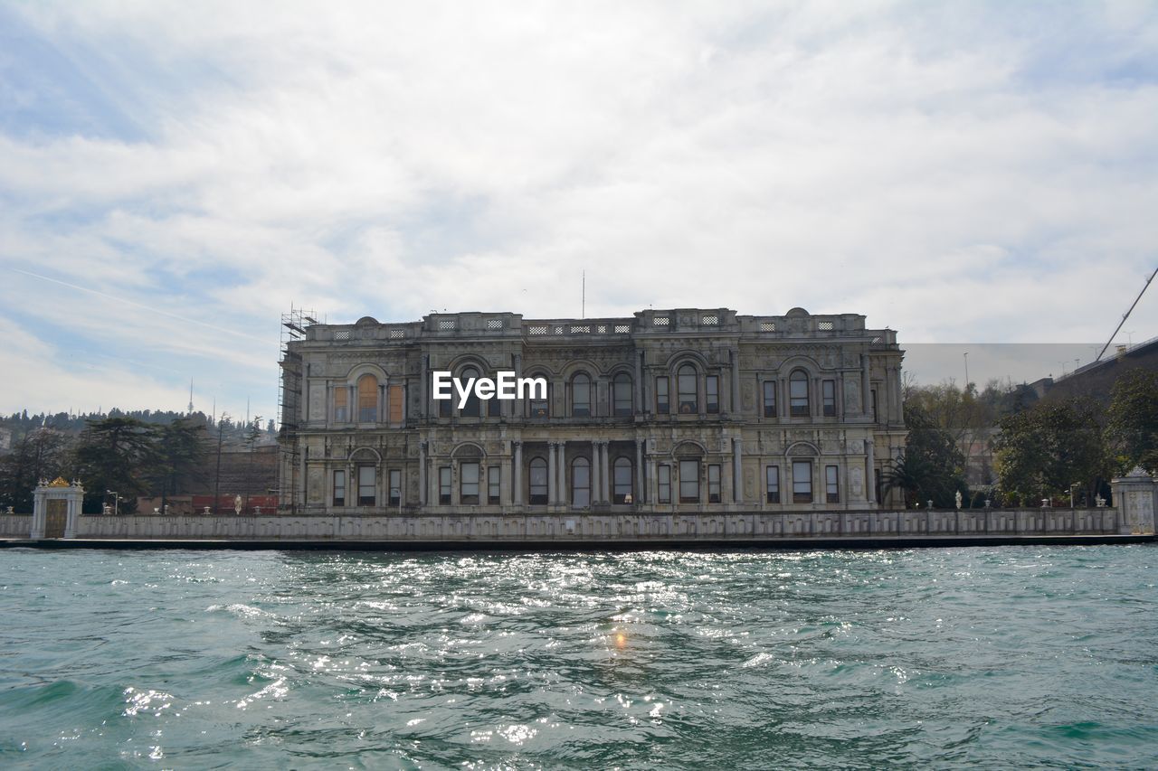 View of building by sea against cloudy sky