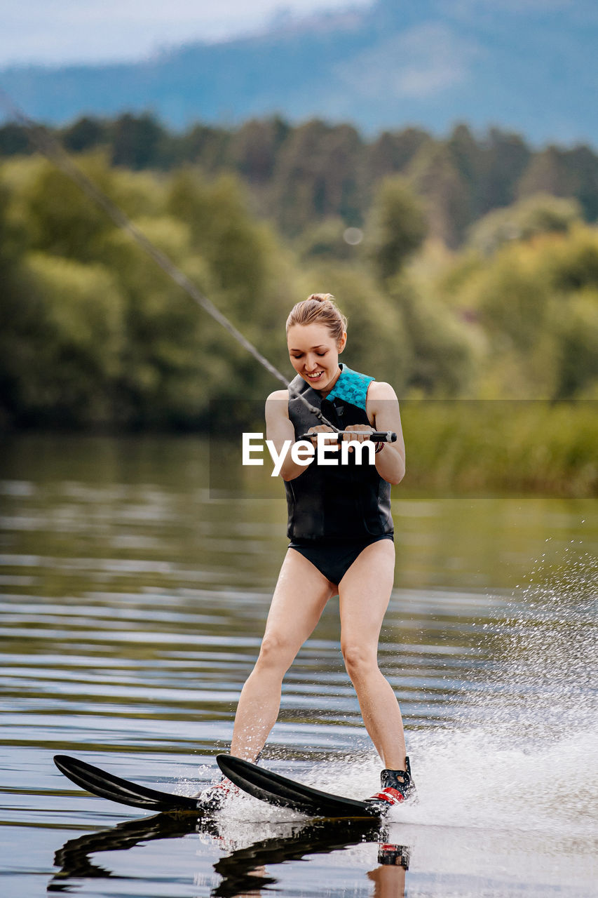 Full length of woman wakeboarding in lake