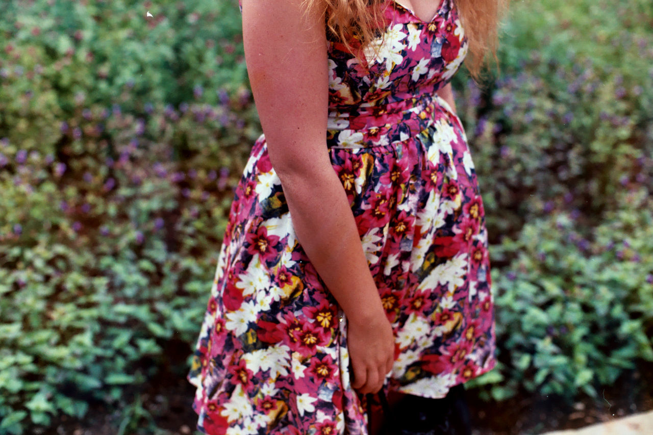 Midsection of woman standing against plants at public park