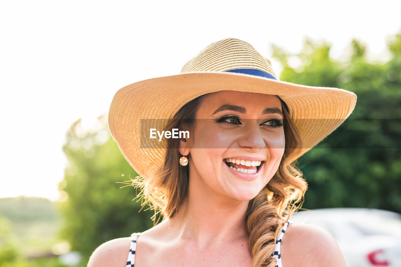 PORTRAIT OF SMILING YOUNG WOMAN WITH HAT