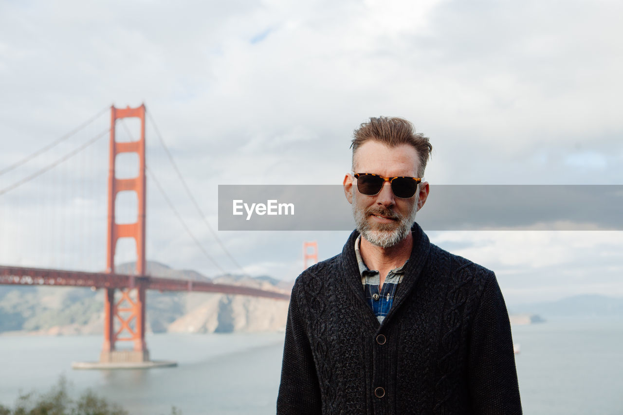 Portrait of adult man with beard and sunglasses with golden gate bridge in background