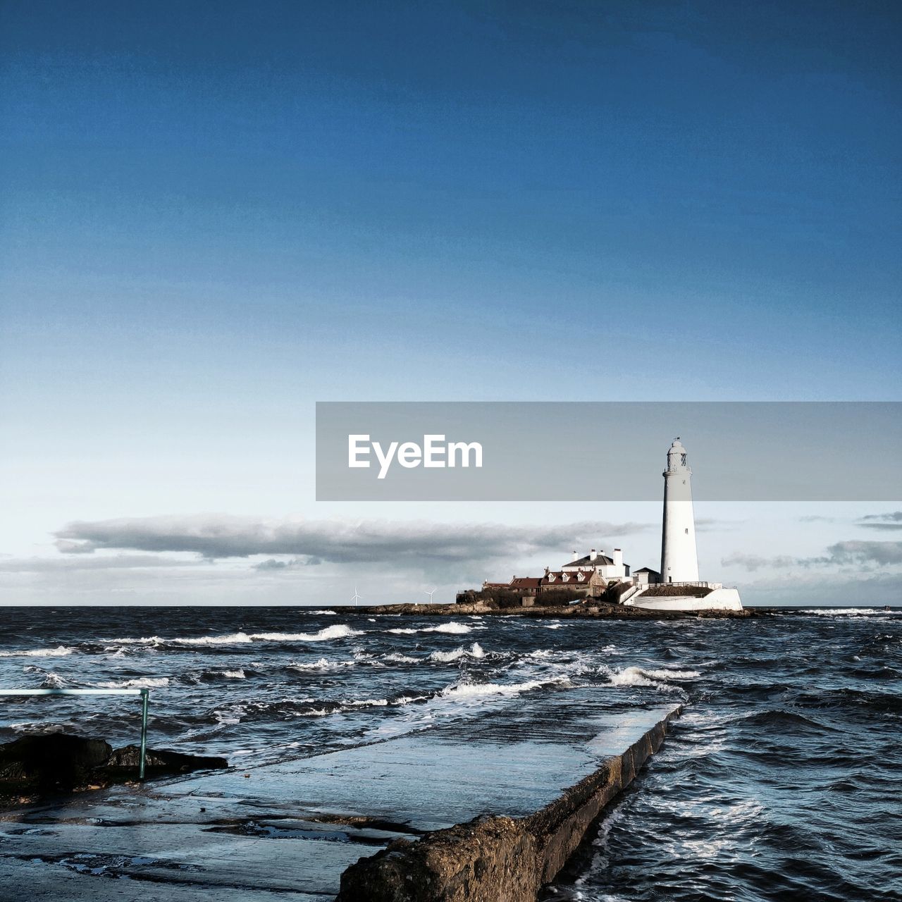 Lighthouse by sea against clear sky