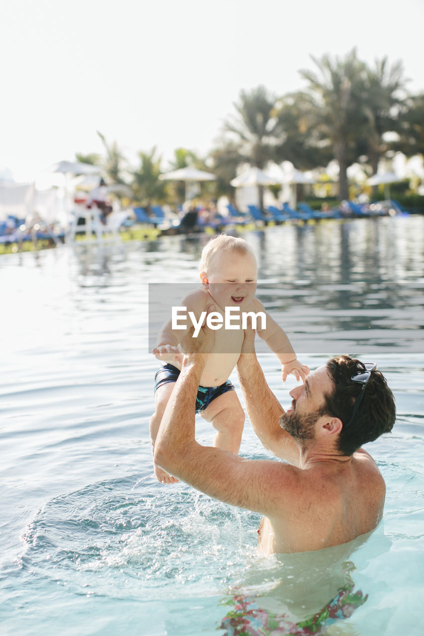 Father playing with baby in swimming-pool