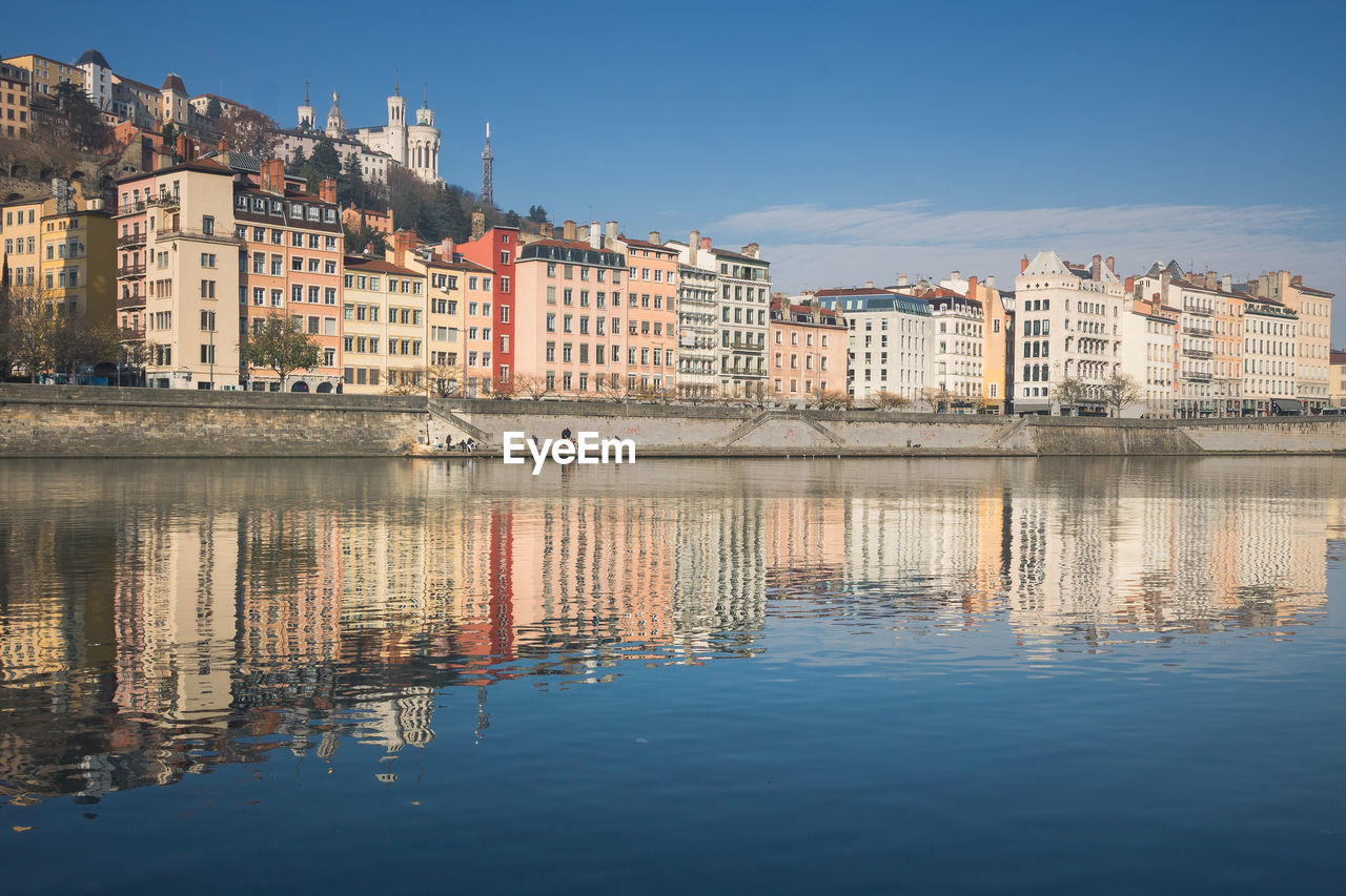 Reflection of buildings in lake against blue sky