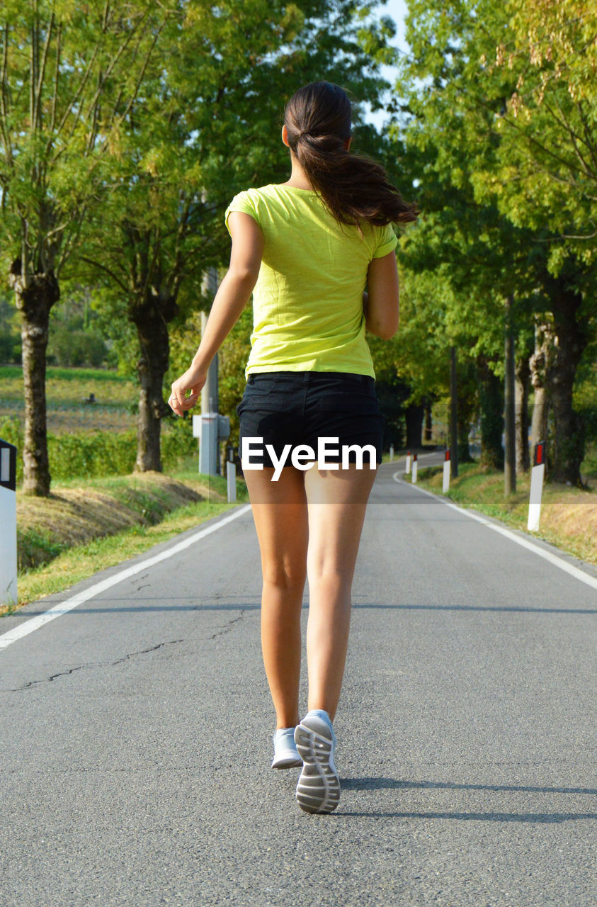 Woman jogging on road against trees