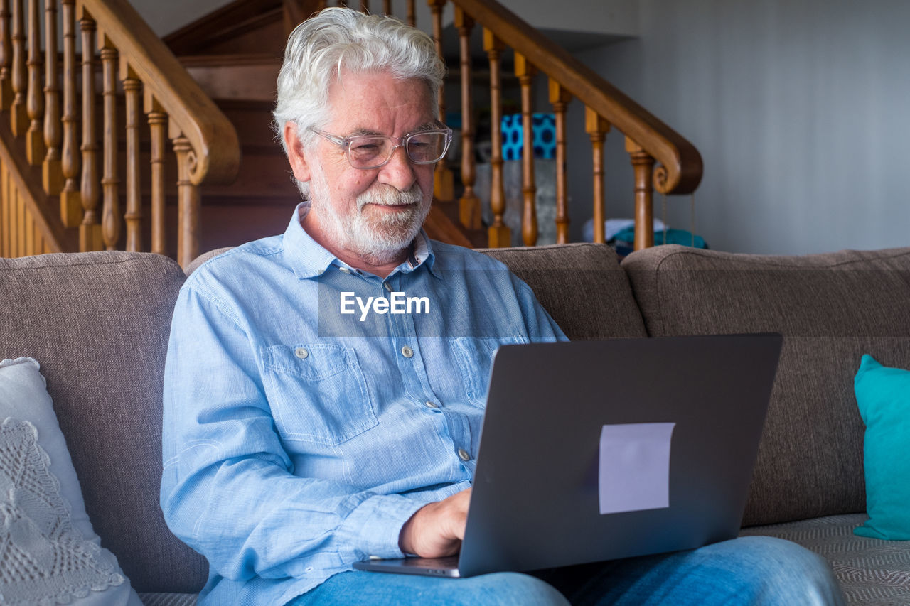 Man using laptop while sitting on sofa at home