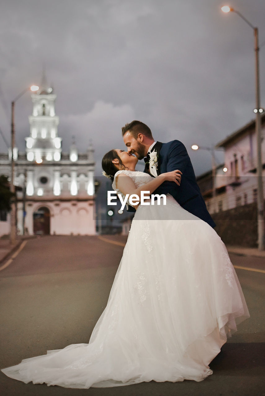 Couple holding camera while sitting on wall