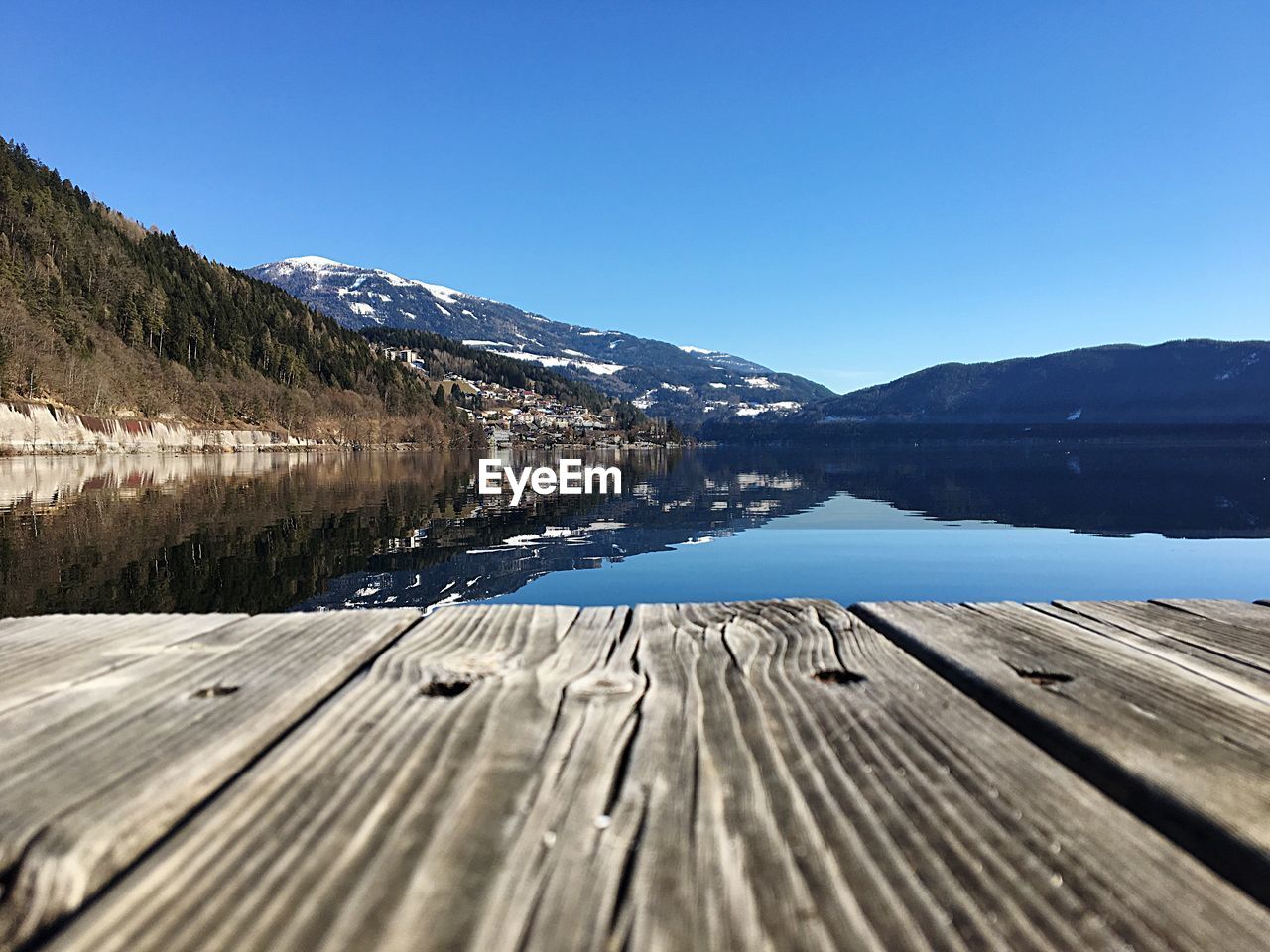 Scenic view of lake by mountains against clear blue sky