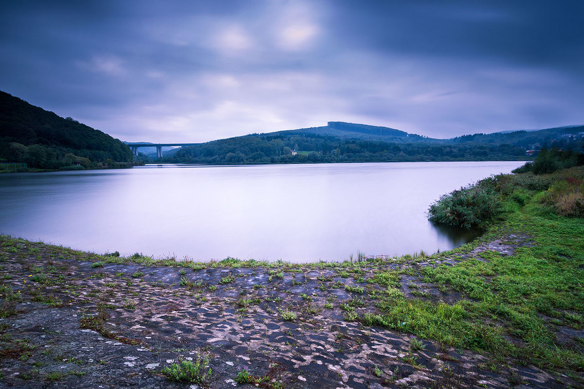 Scenic view of calm lake against cloudy sky