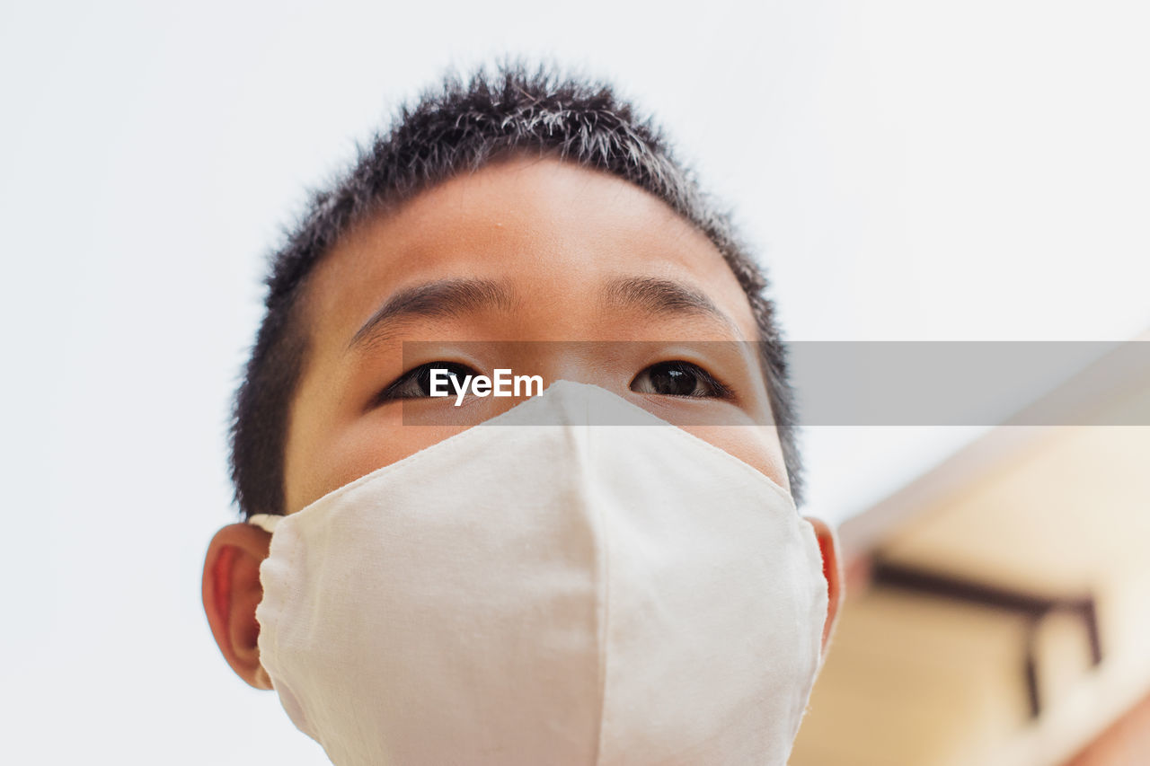 Close-up of boy wearing mask against clear sky