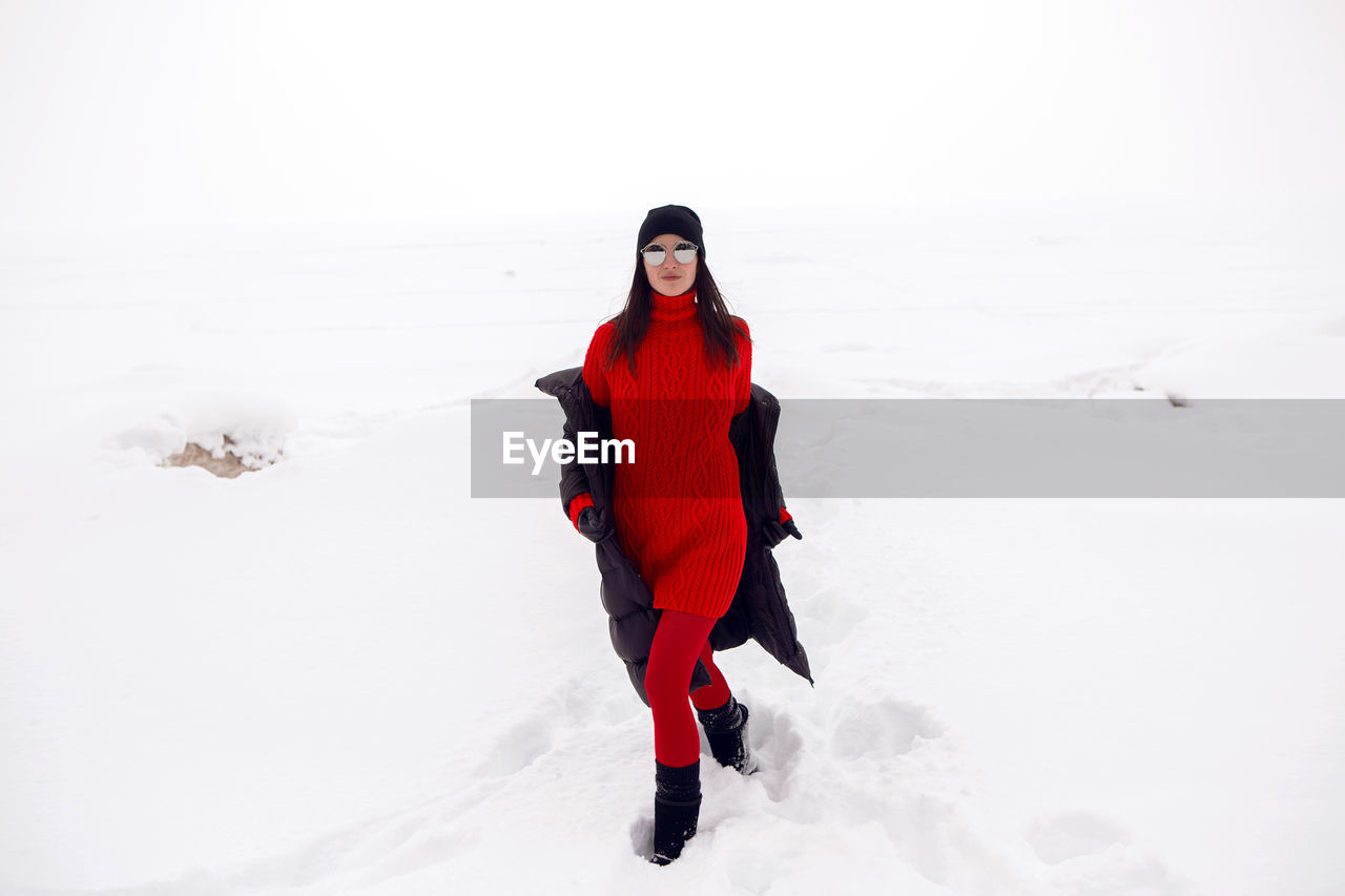 Girl running in a snowy field in a jacket and sunglasses