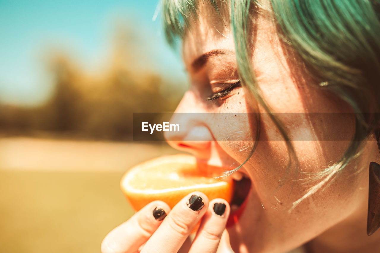 Close-up of woman eating orange fruit