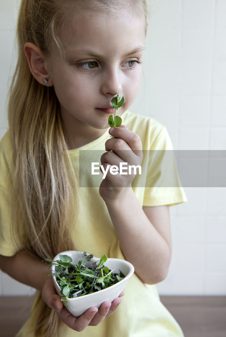 Little girl holding a bowl with microgreens in her hands. healthy eating concept