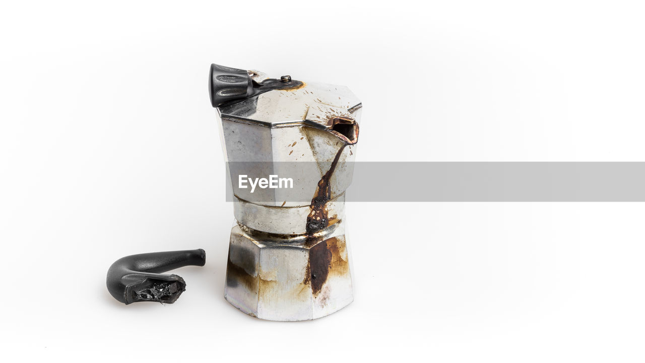 Close-up of broken coffee maker over white background