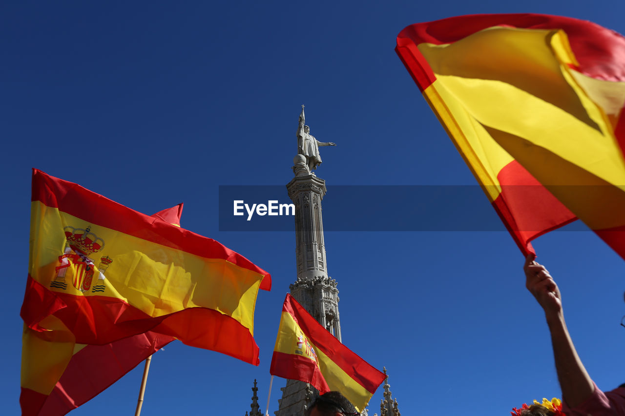 LOW ANGLE VIEW OF FLAGS AGAINST BLUE SKY