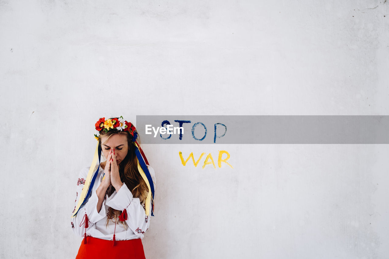 Woman with hands clasped against wall