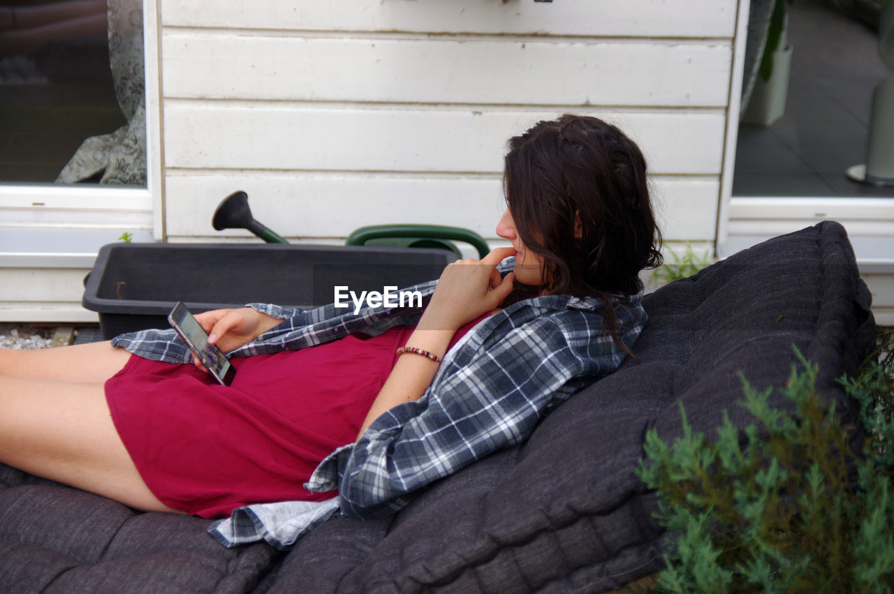 Young woman using phone on sofa
