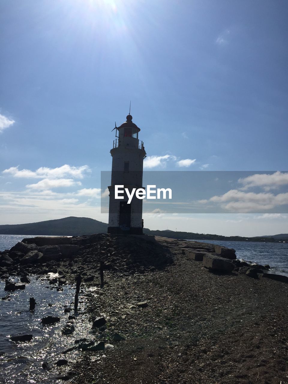 Lighthouse by sea against sky