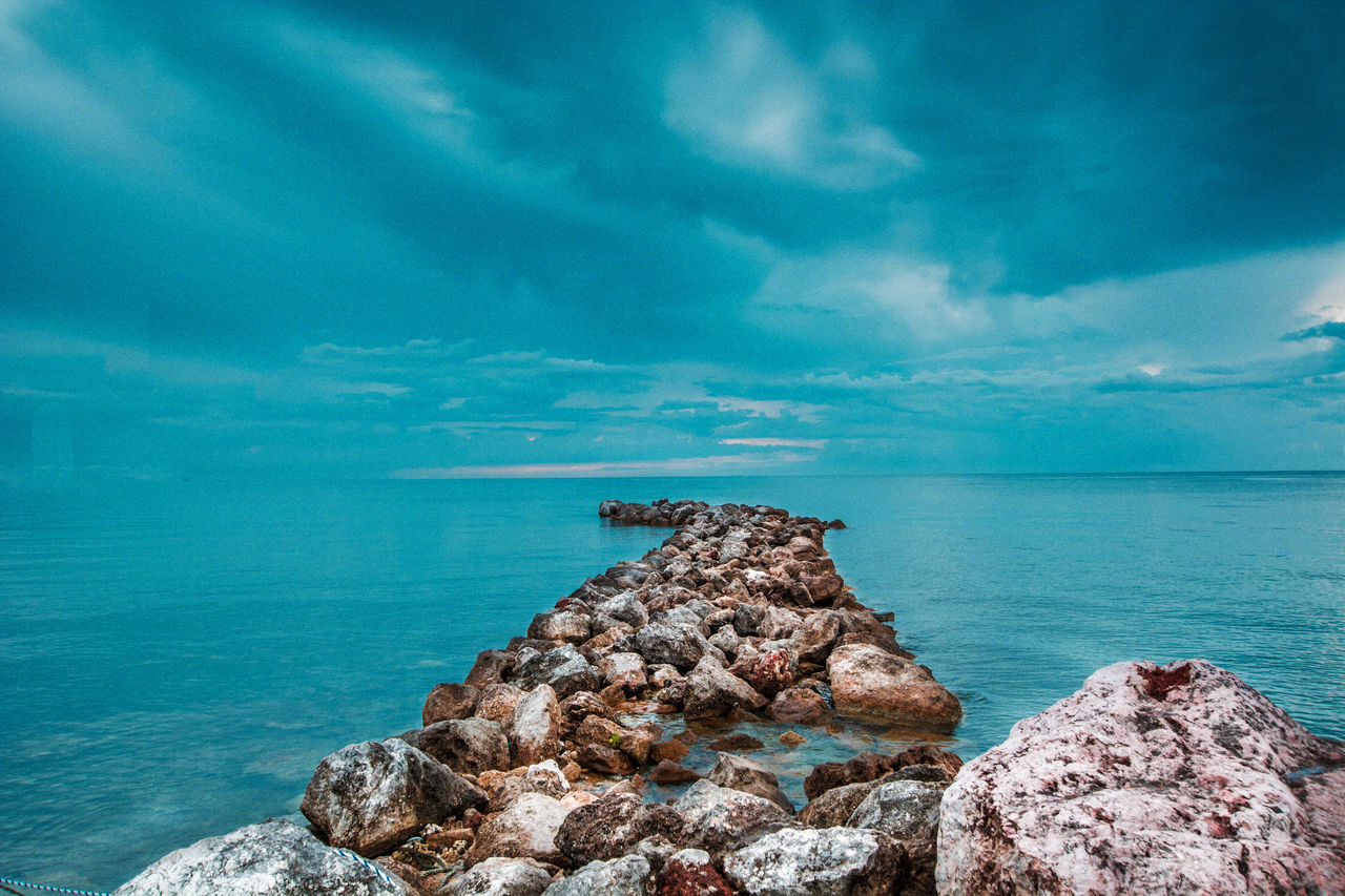 Rock formation by sea against blue sky