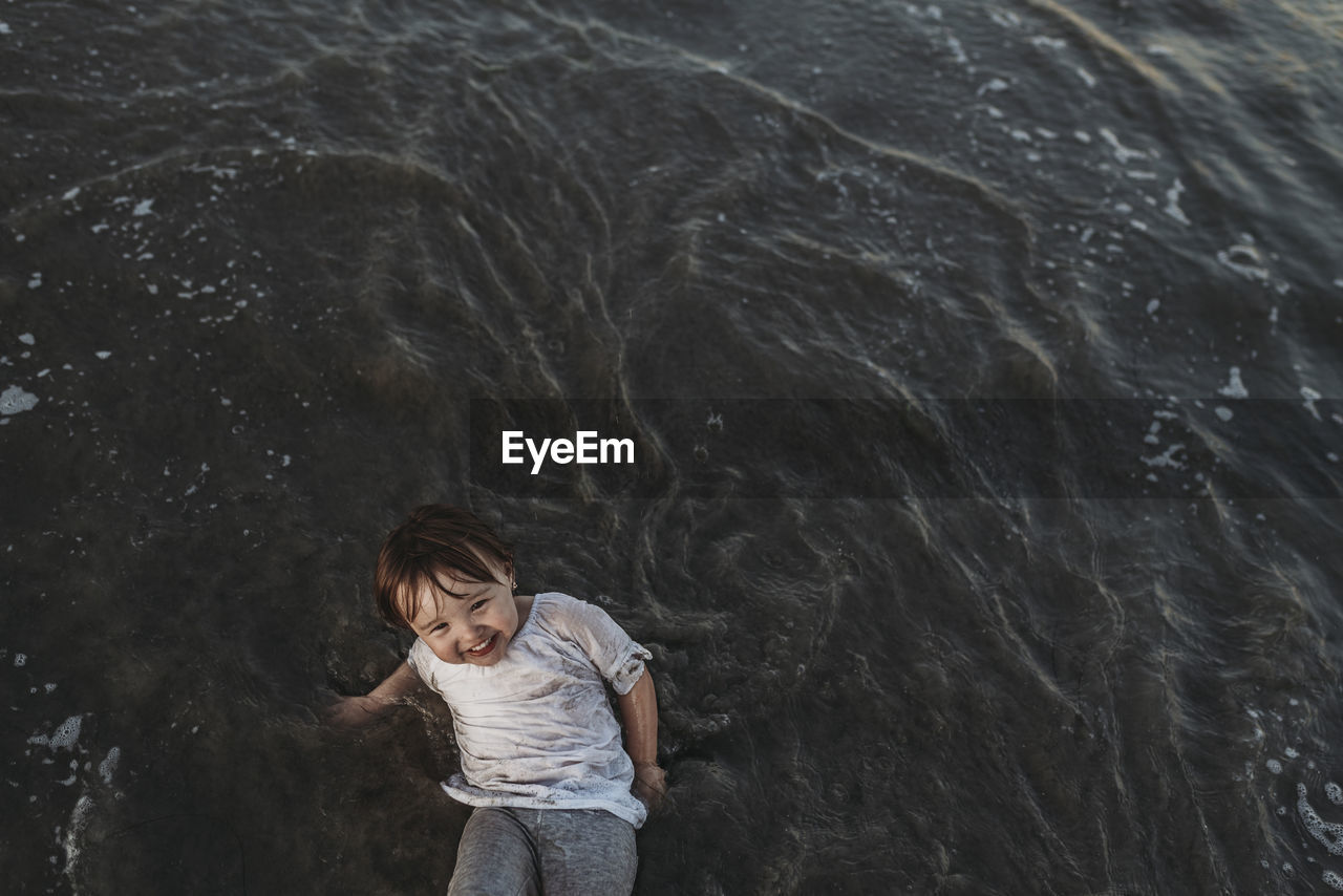 High angle view of happy toddler girl playing in ocean