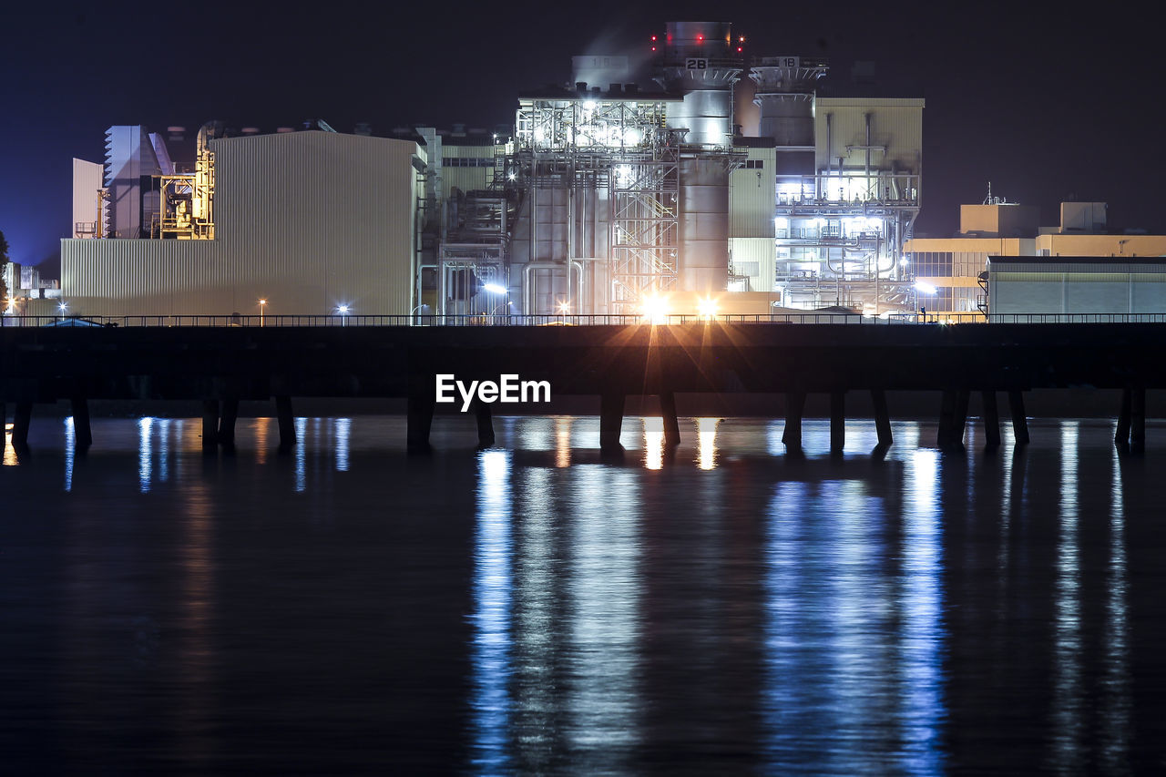 ILLUMINATED BUILDINGS BY SEA AGAINST SKY