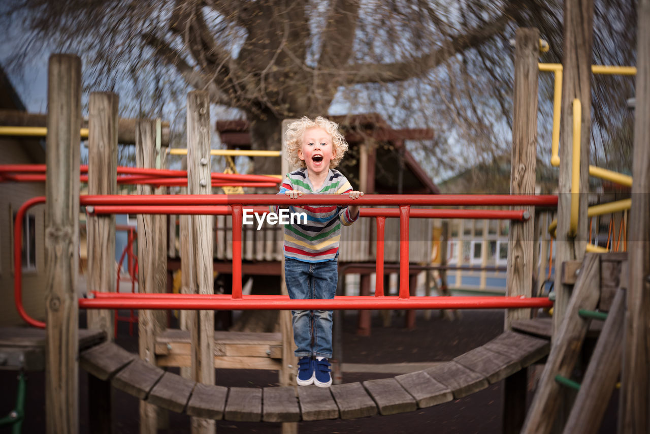 Young boy laughing and playing on playground at a park