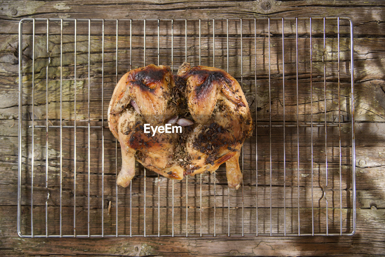 Directly above shot of roast chicken on rack over wooden table
