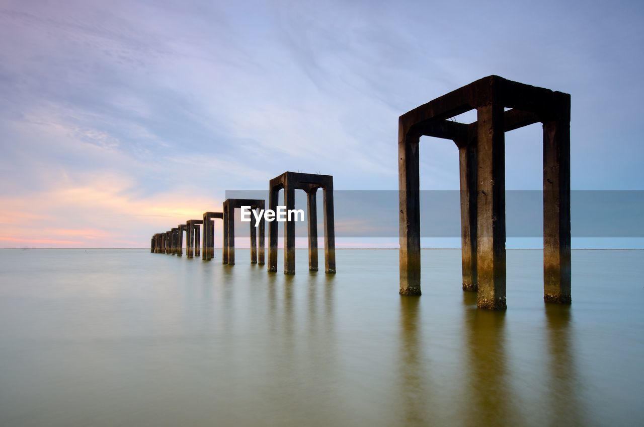 Wooden pier on sea against sky during sunset