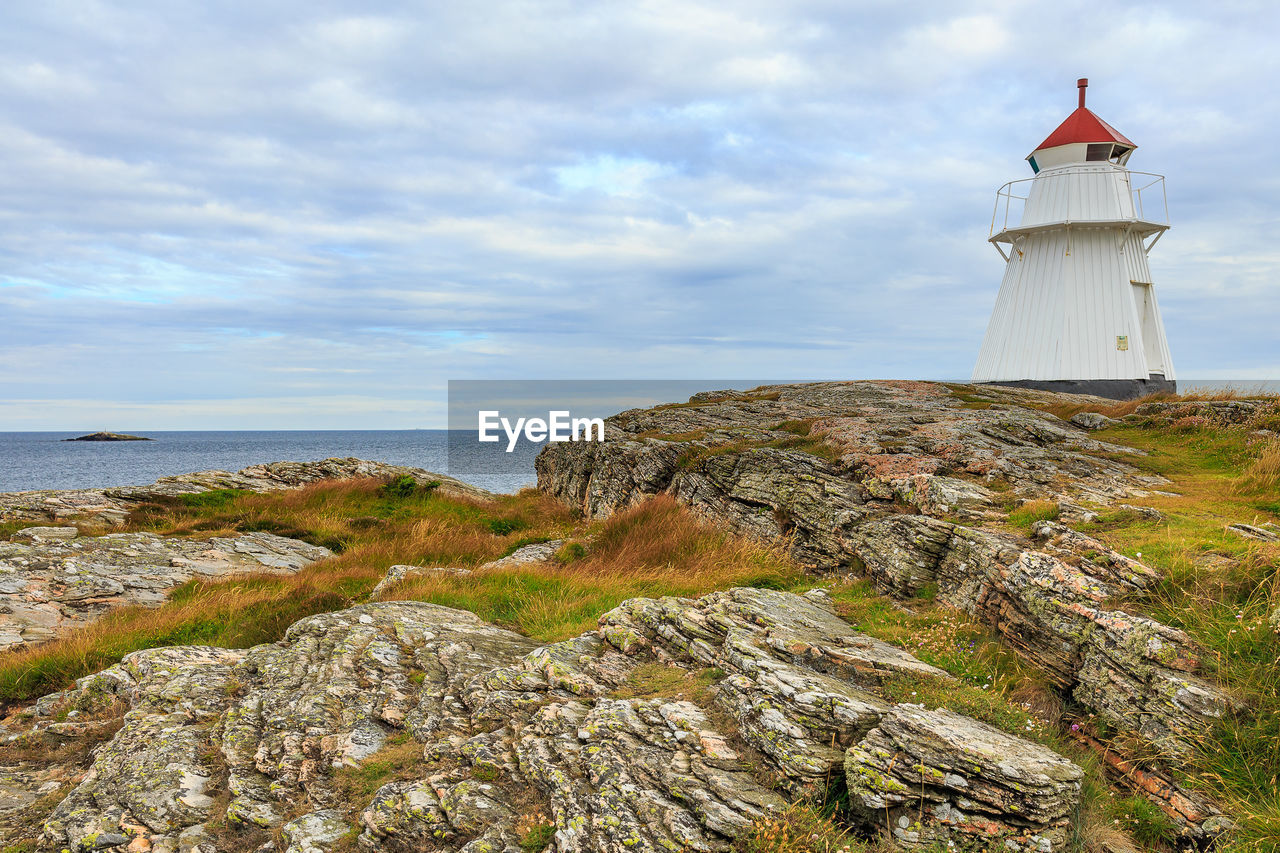 Lighthouse by sea against sky