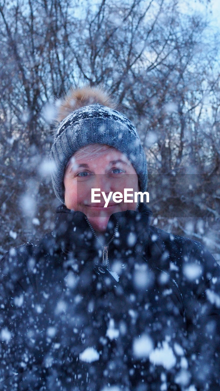 Portrait of smiling woman in snow fall