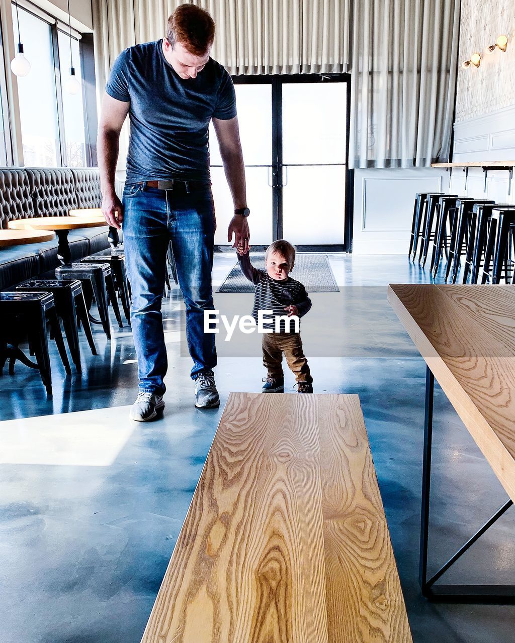 Father and son holding hands while walking on floor