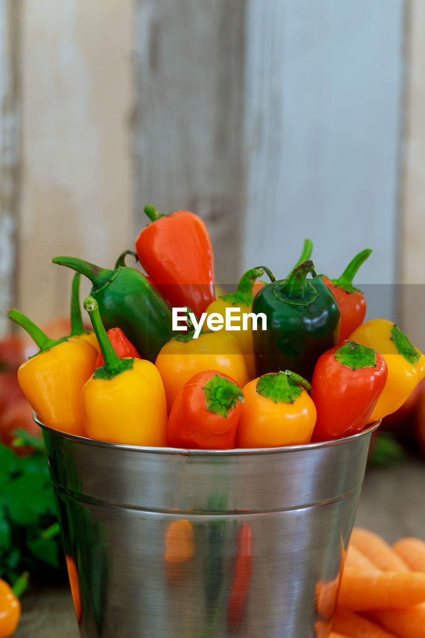 Close-up of multi colored bell peppers in container on table