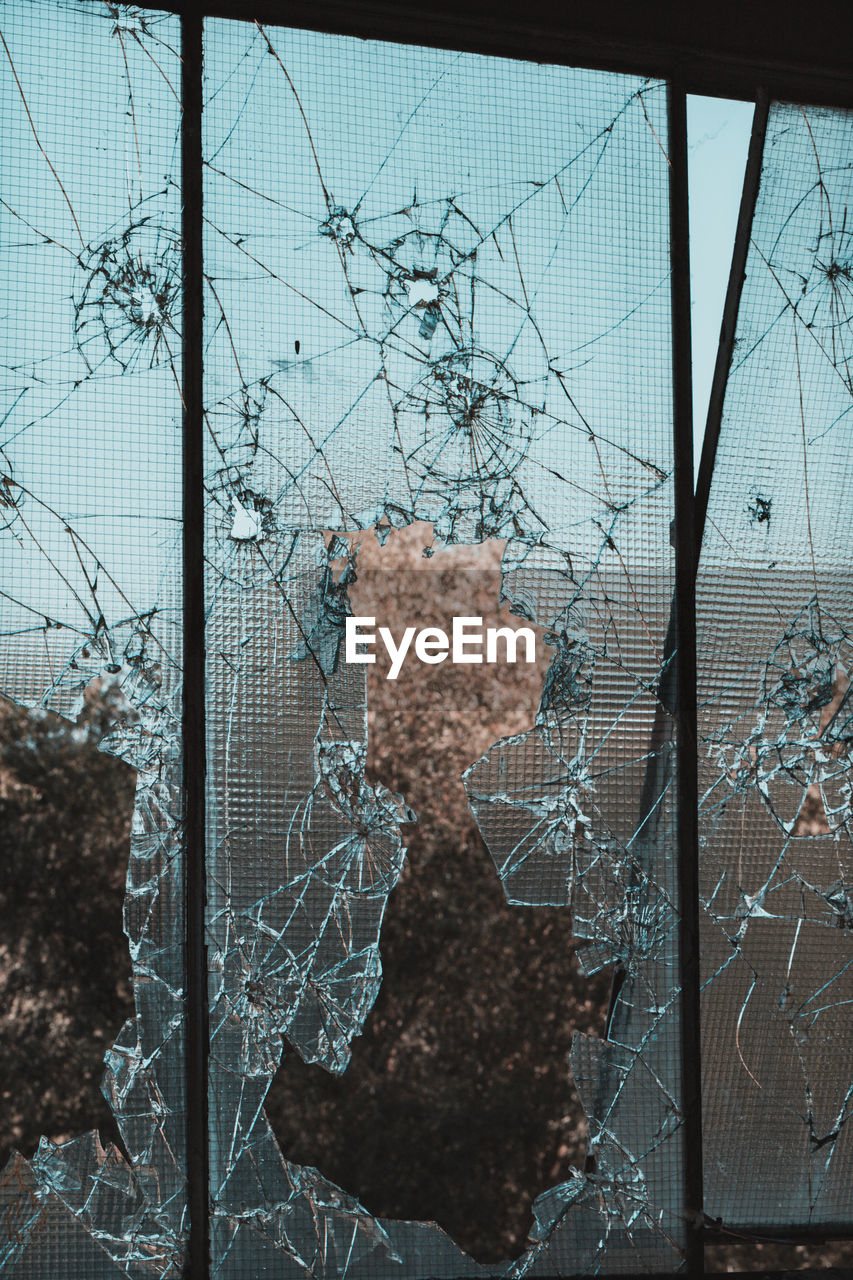 CLOSE-UP OF BROKEN GLASS WINDOW AGAINST SKY