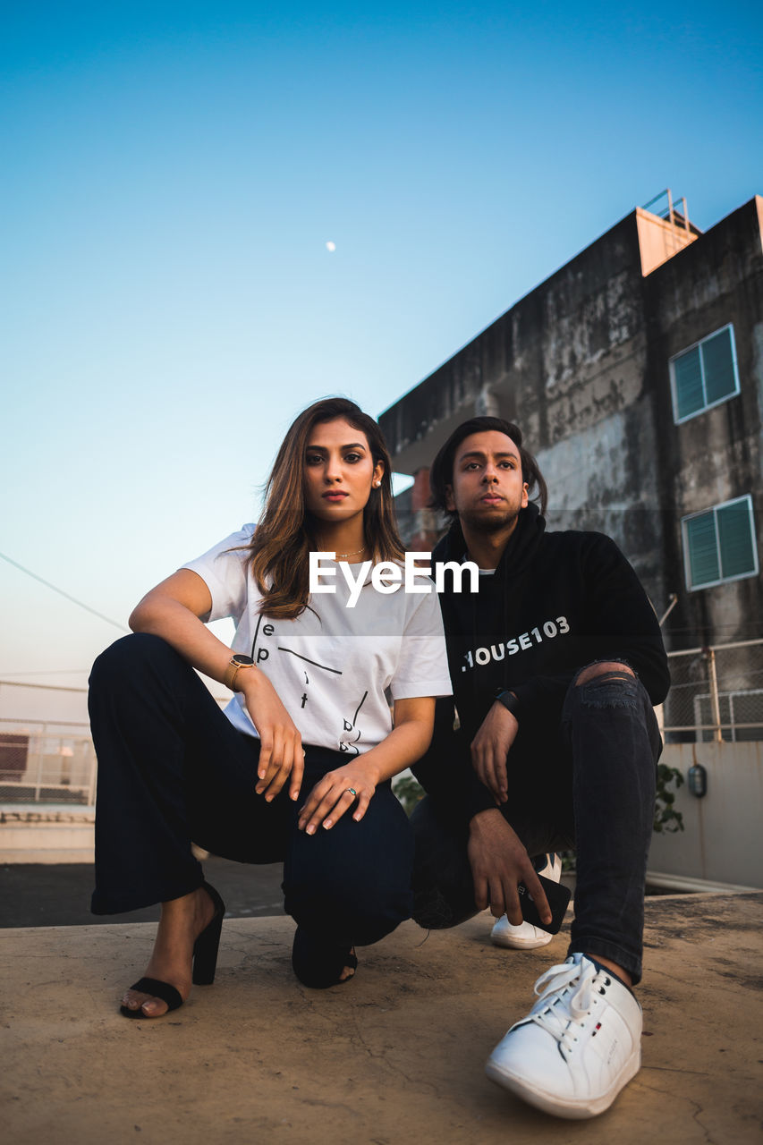 YOUNG COUPLE STANDING AGAINST BUILDING