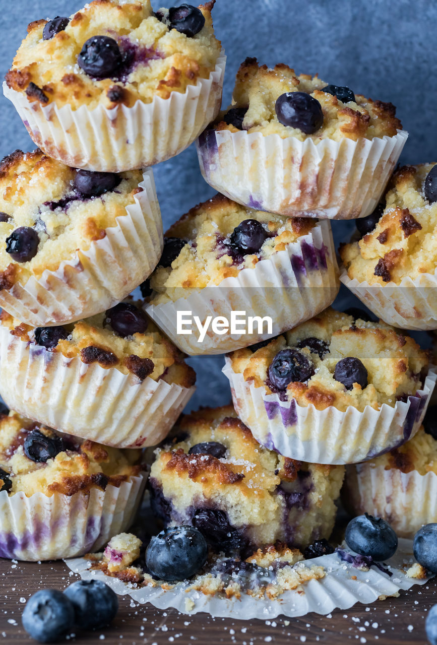 Freshly made blueberry muffins stacked high against a blue background.