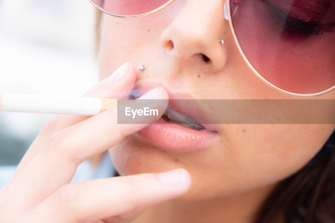 Close-up of woman in sunglasses smoking cigarette