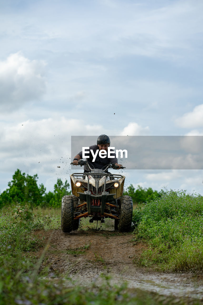 Man riding atv on plants against sky