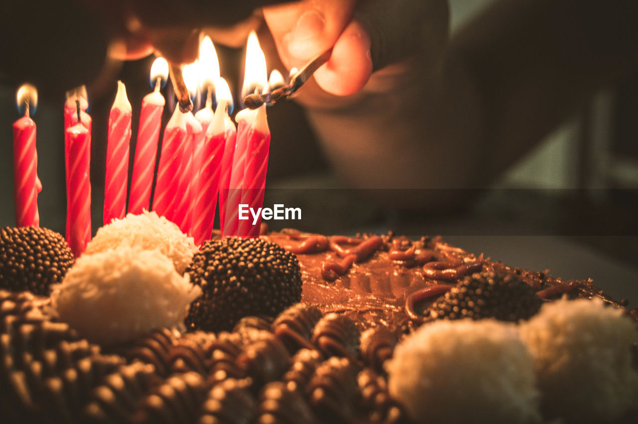 Cropped hand burning candles on birthday cake