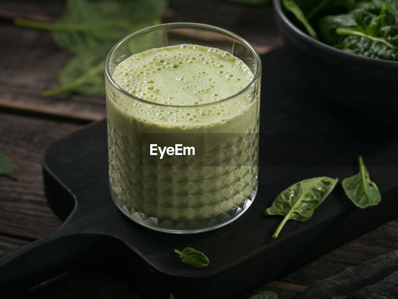 Glass of homemade healthy green smoothie with fresh baby spinach