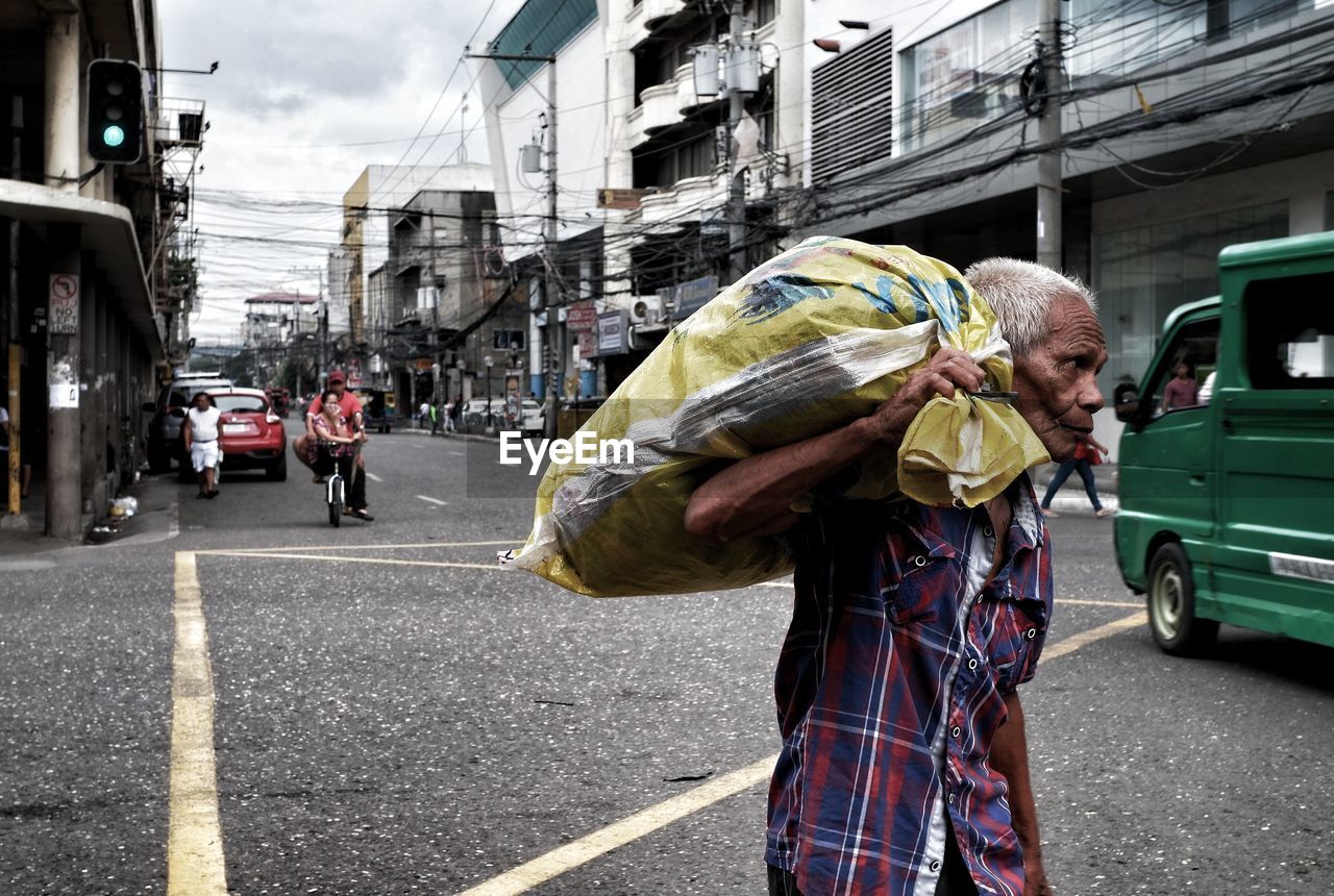 Senior man carrying sack while walking on street