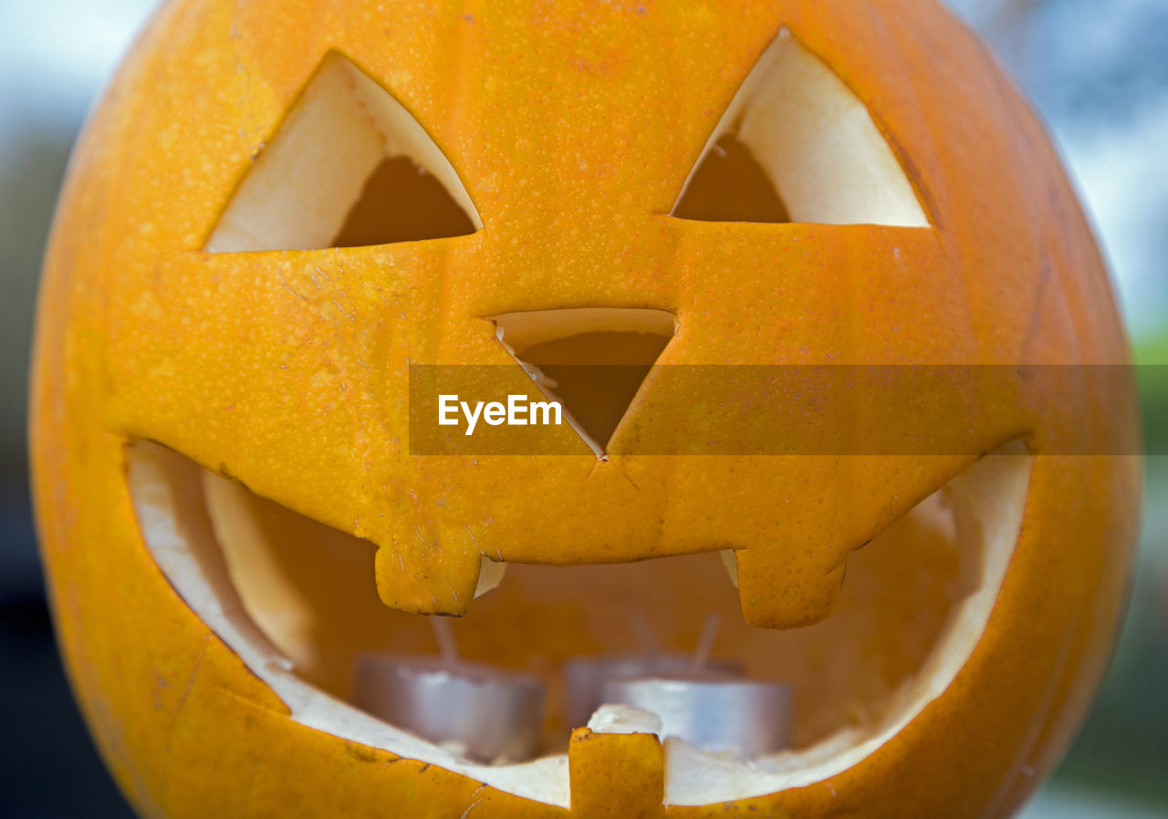 CLOSE-UP OF HALLOWEEN PUMPKIN ON YELLOW WALL