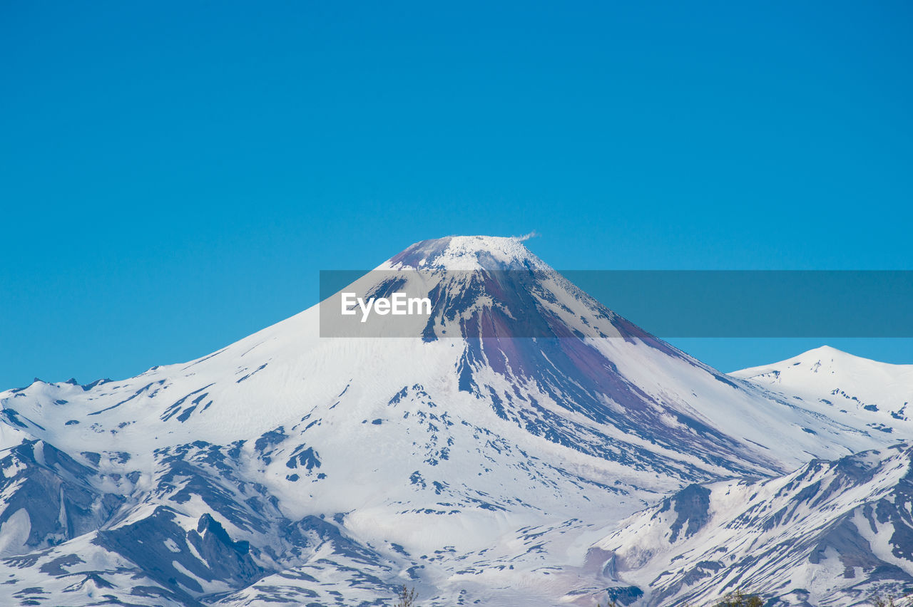 Scenic view of snowcapped mountains against clear blue sky